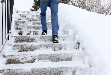 Person walking up snowy outdoor steps.